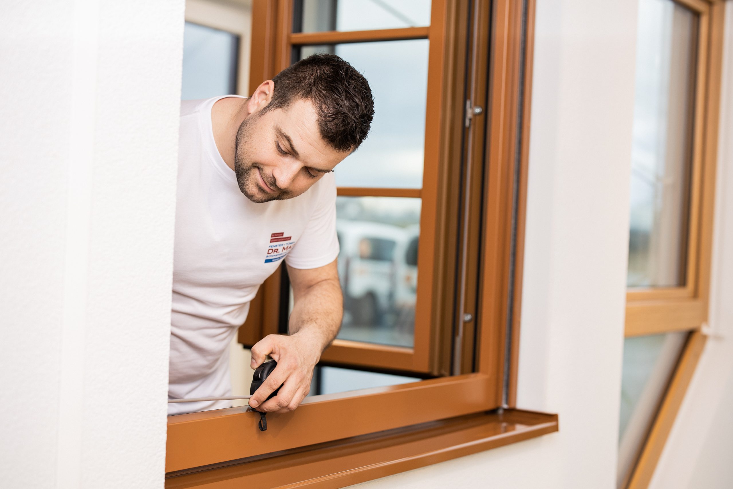 Person beim Ausmessen eines geöffneten Fensters mit einem Maßband
