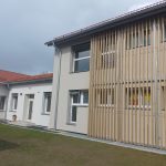 Schul- und Kindergartengebäude in Kitzeck mit Fenstern und Holzlamellen an der Fassade