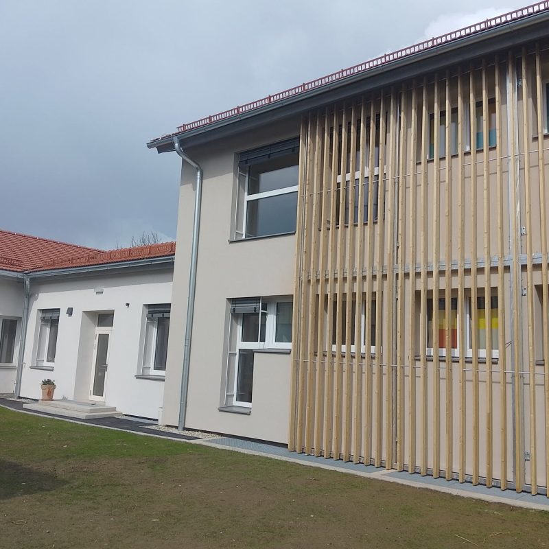 Schul- und Kindergartengebäude in Kitzeck mit Fenstern und Holzlamellen an der Fassade