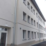 Lange Fassade des Schul- und Kindergartengebäudes in Kitzeck mit hell gerahmten Fenstern und außenliegendem Sonnenschutz