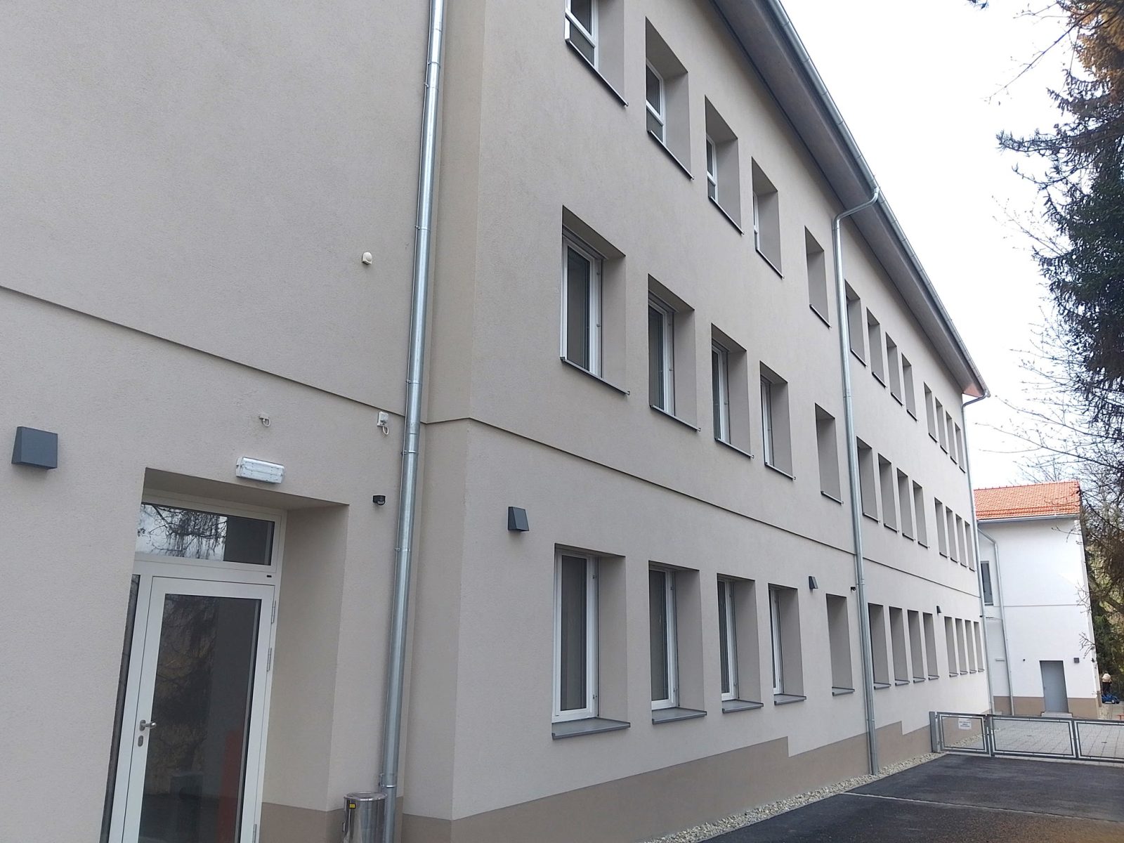 Lange Fassade des Schul- und Kindergartengebäudes in Kitzeck mit hell gerahmten Fenstern und außenliegendem Sonnenschutz